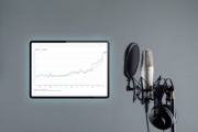 Diagramme auf Tabletbildschirm mit Podcast-Mikrofon