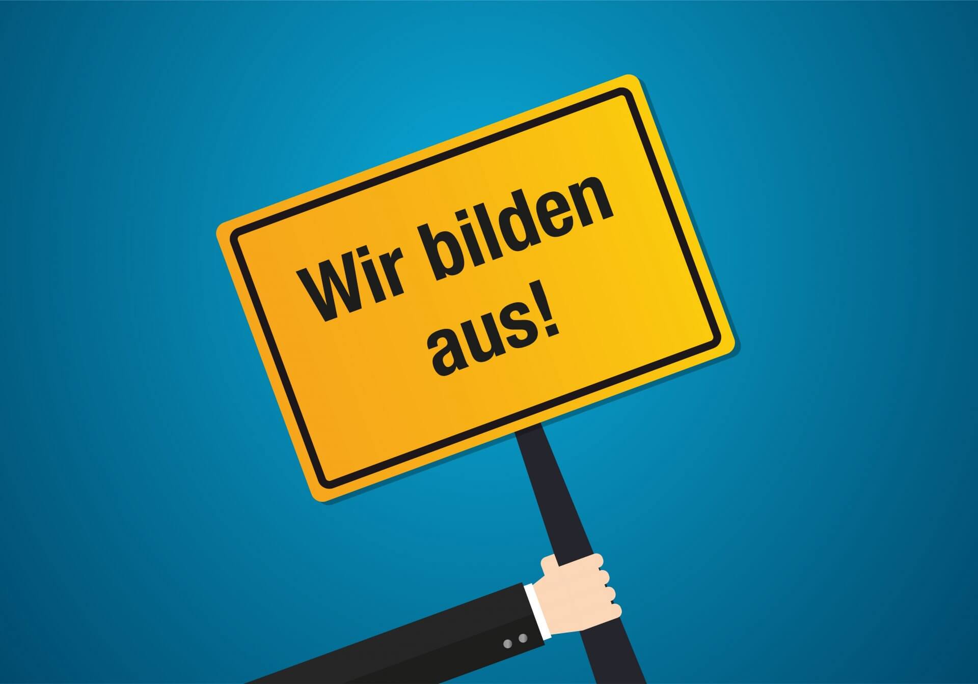 Schild "Wir bilden aus!" vor blauem Grund (iStock-1329056202)