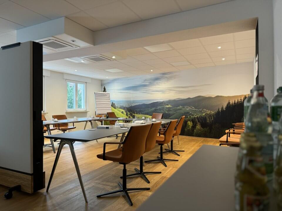 Bild des Sitzungssaals der RAK Freiburg mit Panorama-Aufnahme von Horben im Hintergrund - bestuhlt für Hybrid-Unterricht.